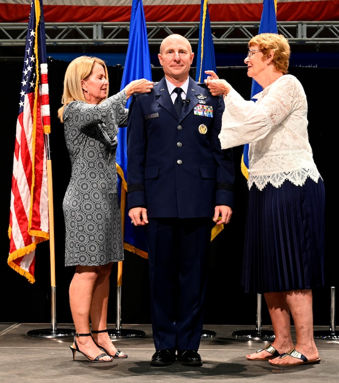 Lt. Gen. Carl Schaefer, Air Force Materiel Command Deputy Commander, stands and smiles while his family pins the rank of lieutenant general on his uniform Aug. 7 at the National Museum of the United States Air Force, Wright-Patterson Air Force Base, Ohio. (photo by Darrius Parker)