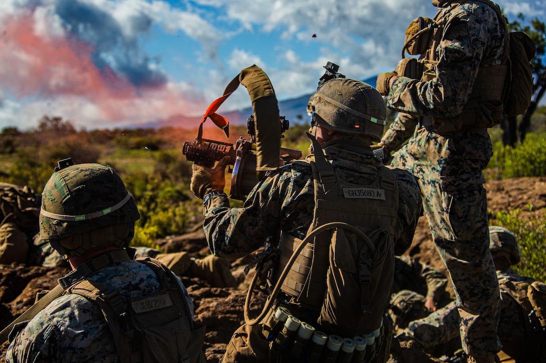 A Marine fires a grenade launcher while others stand around him.