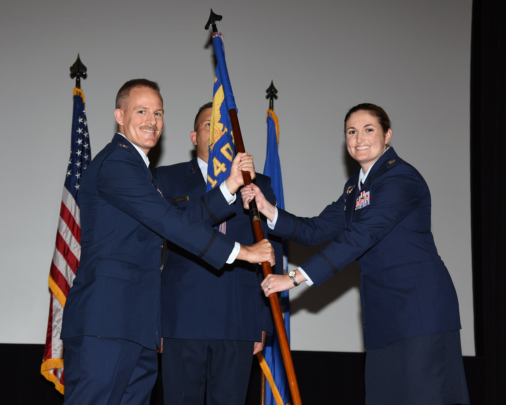 Col. Justin Spears, 14th Operations Group commander, hands Lt. Col. Jennifer Prouty, 14th Operations Support Squadron commander, the 14th OSS guidon at the 14th OSS change of command ceremony on Aug. 3, 2020, on Columbus Air Force Base, Miss. The 14th OSS is responsible for producing over 426 new pilots and WSOs annually. (U.S. Air Force photo by Sharon Ybarra)