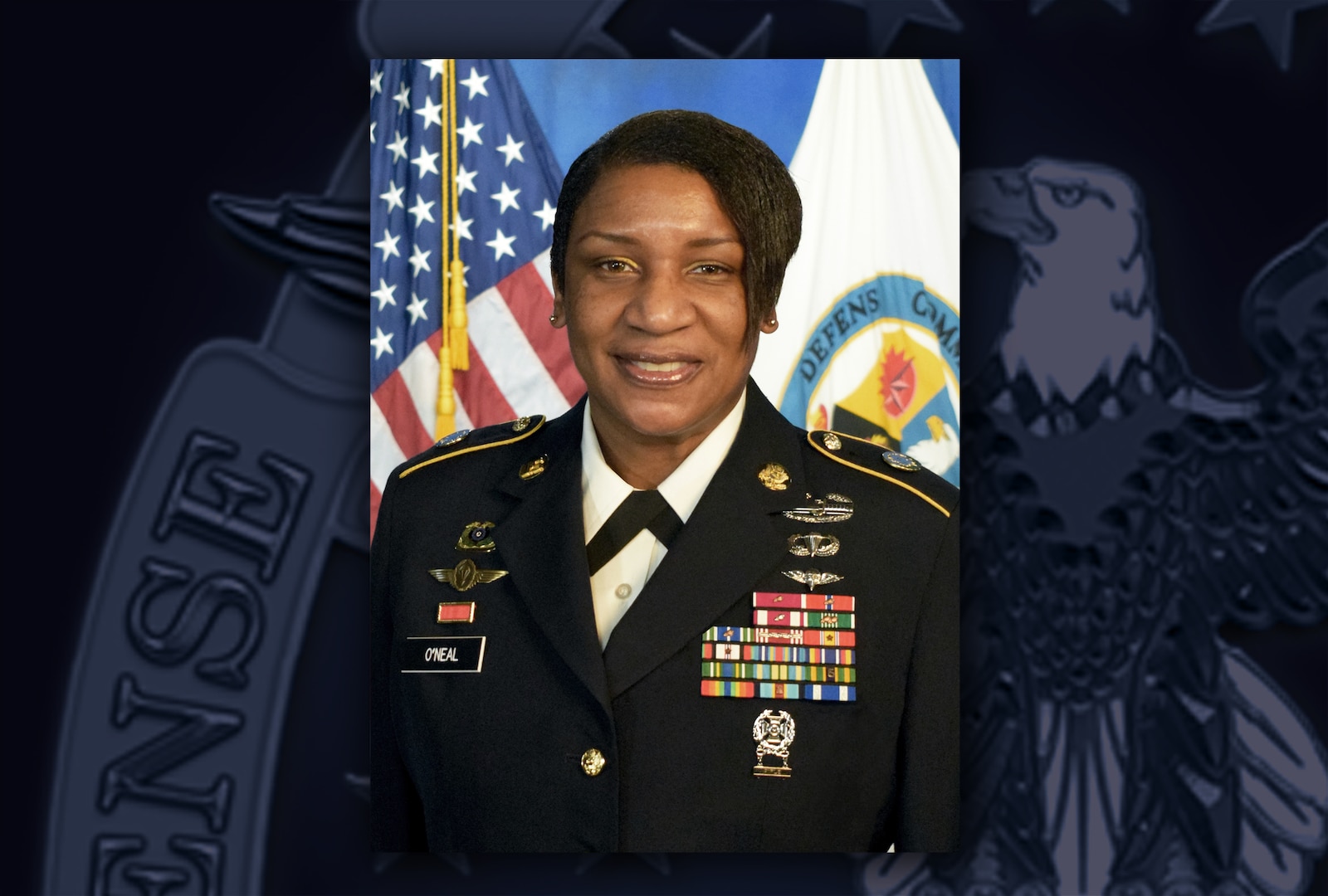 Black woman in Army dress uniform with ribbons and medals sits in front of US and Defense Commissary Agency flags.