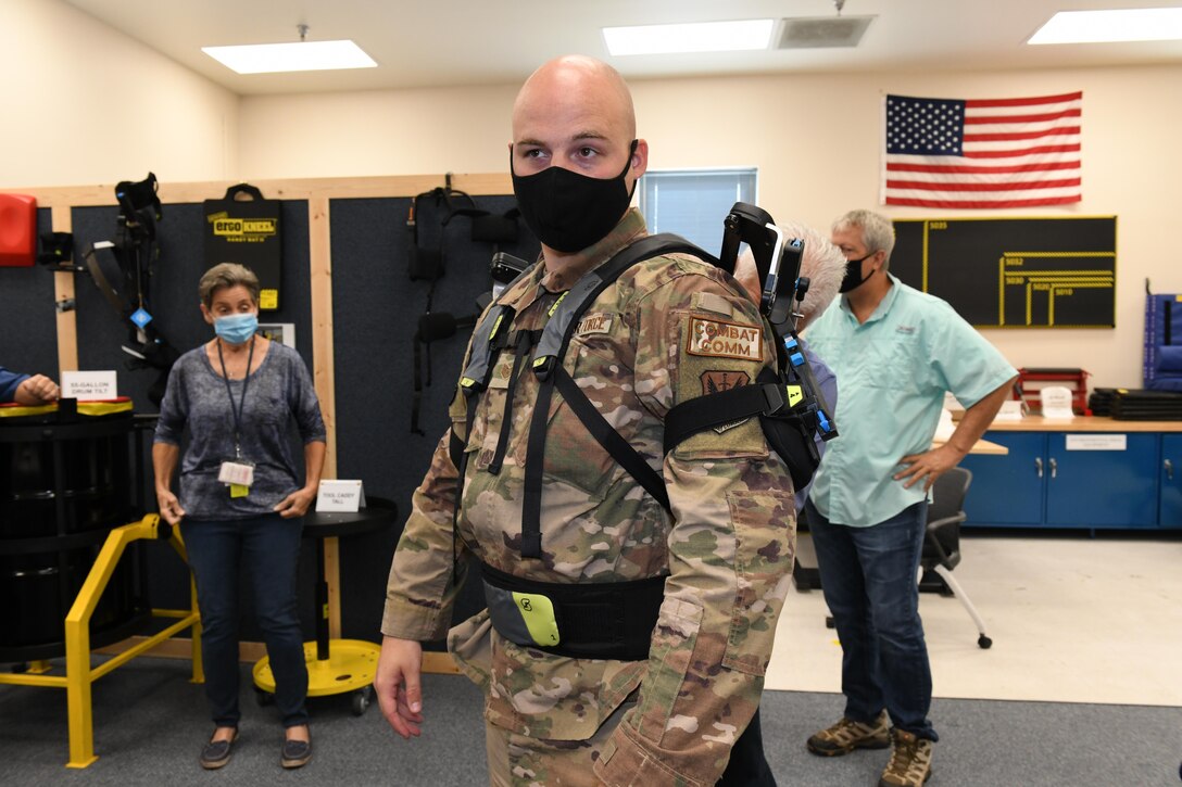 Photo shows a man twisting his upper body with a man and woman in the background observing the movement.