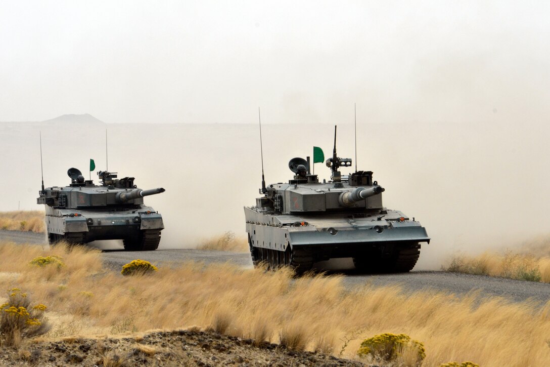 Tanks roll down a road.