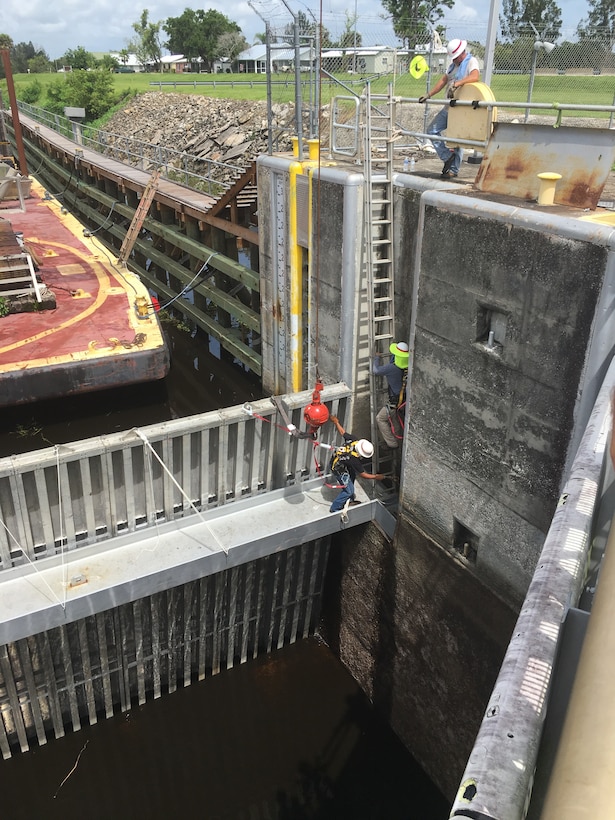 Corps team members wearing safety harnesses hook the crane assembly to the top of the narrow slide plate..