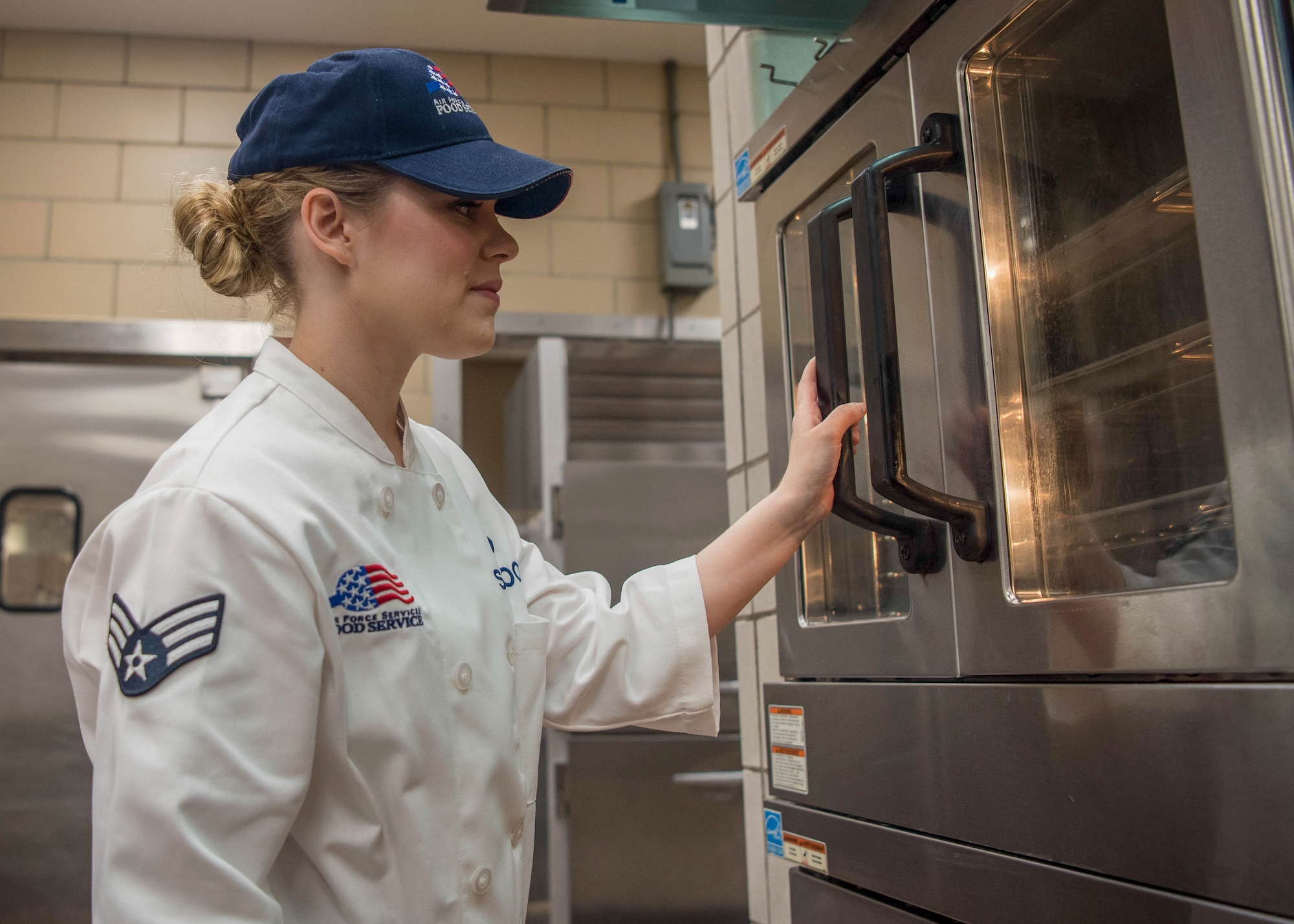 Senior Airman Sherwood prepares to remove food from an oven at Joint Base Langley-Eustis, Virginia.