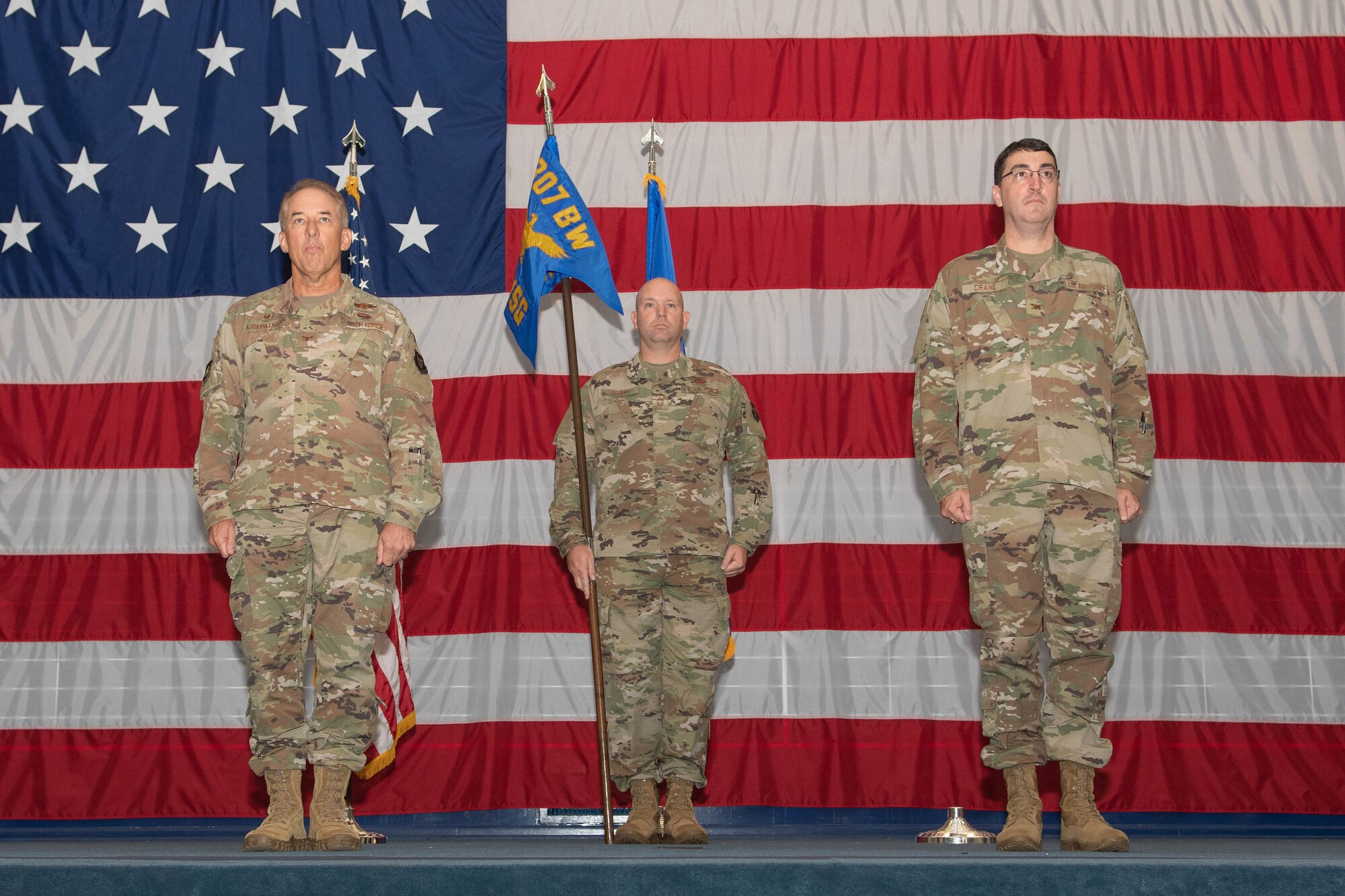 Three airmen stand at attention during command ceremony.