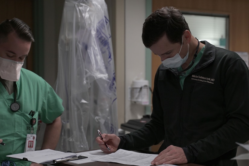 A staff physician goes over paperwork in a COVID-19 intensive care unit.