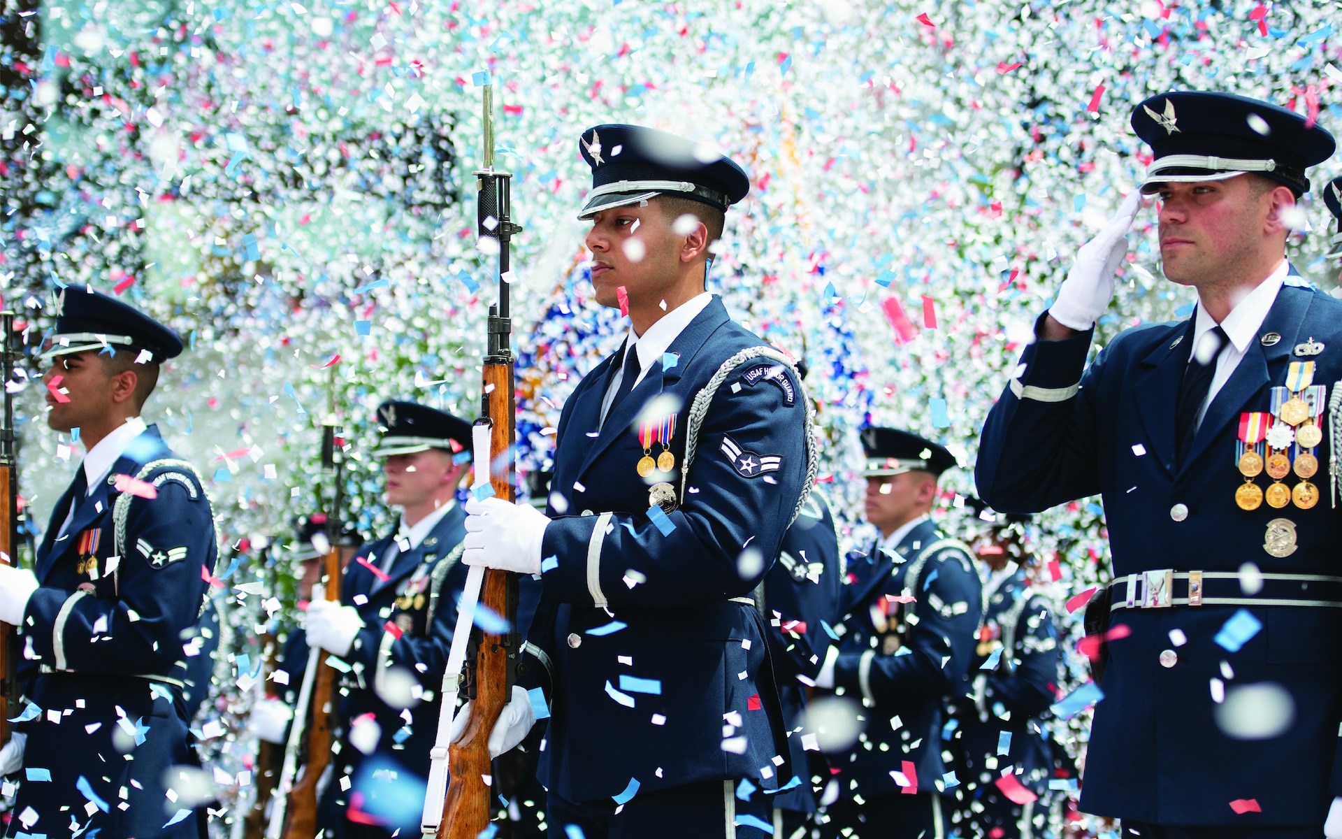 Armed unit of service man dressed in formal uniform standing at attention during a celebration with confetti flying in the air