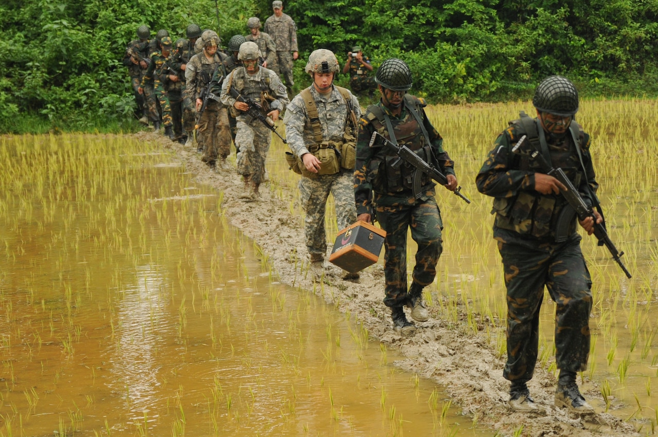 Soldiers march through rice paddy.