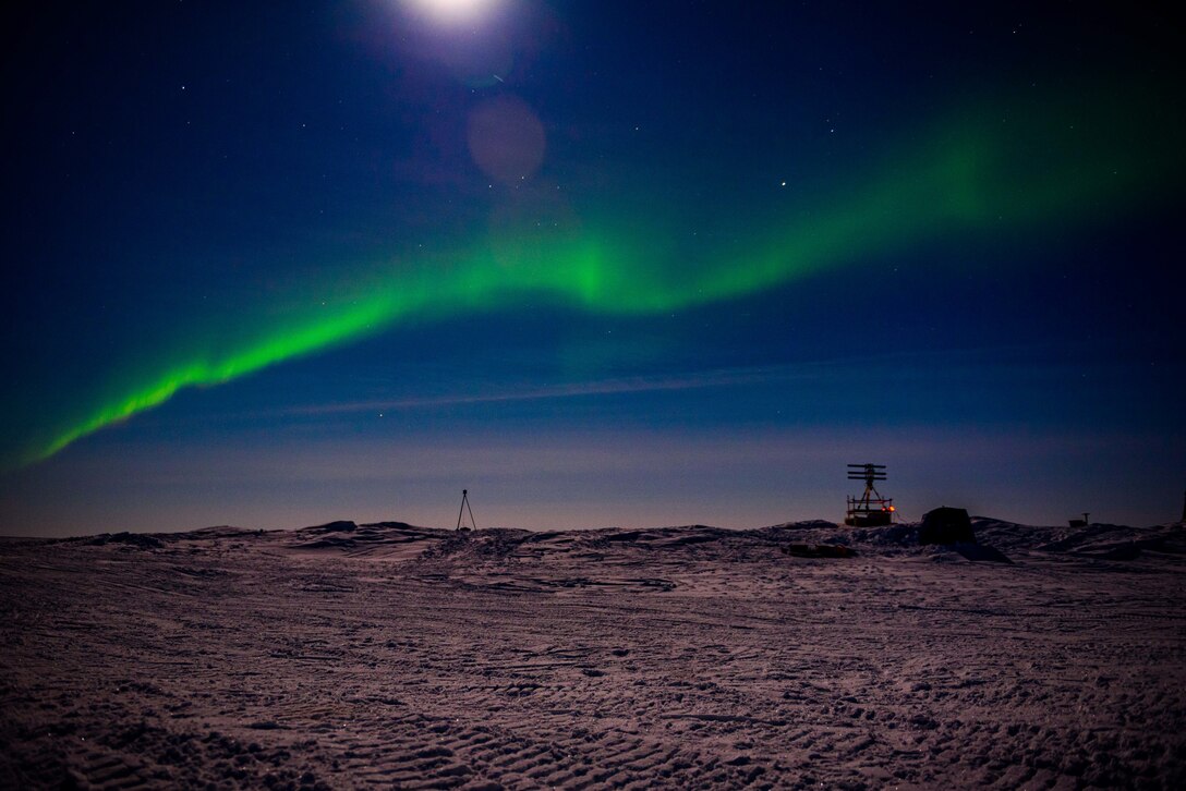 Aurora borealis shines over camp on Arctic ice.
