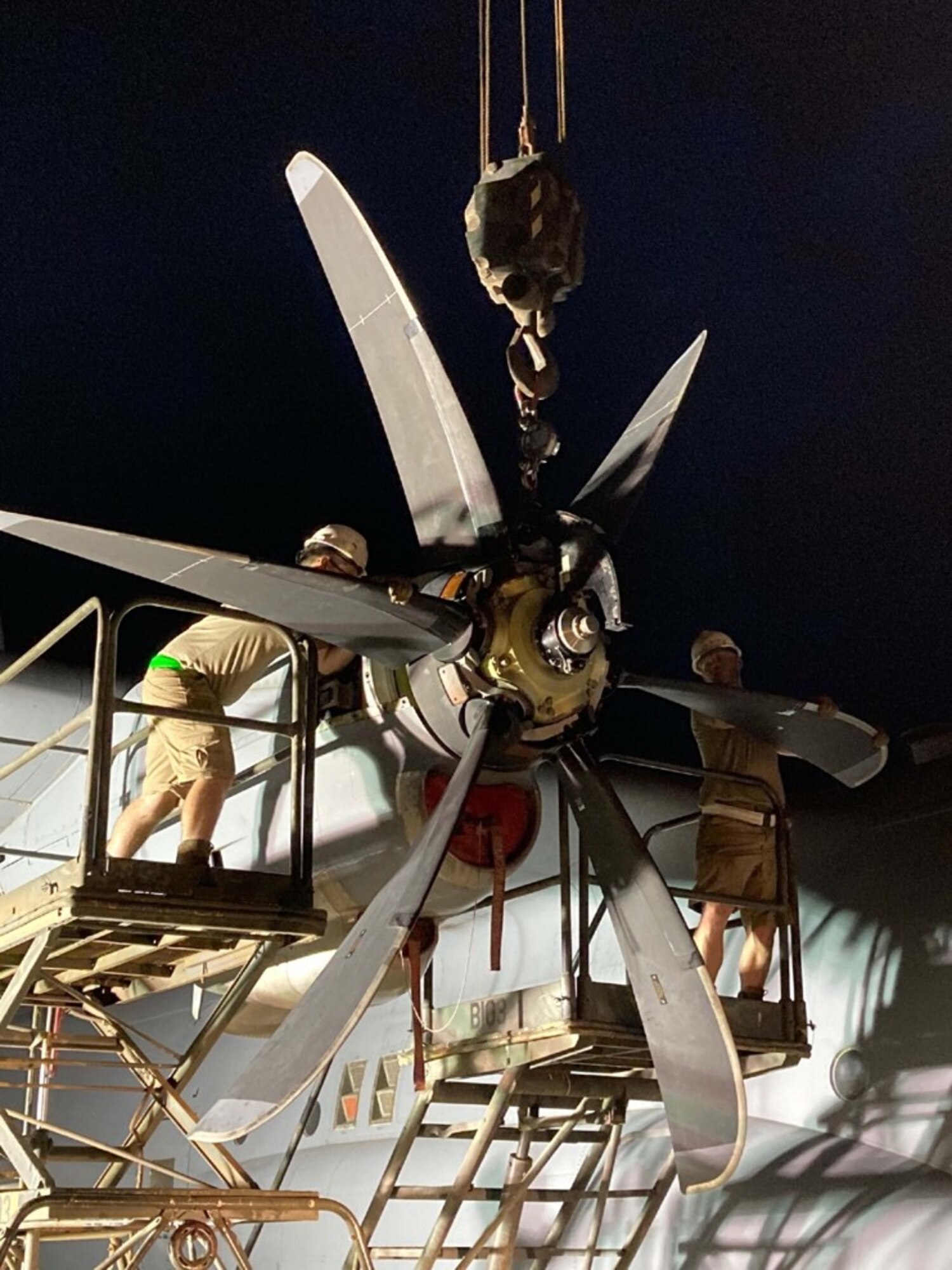 Maintainers fix a propeller on a plane