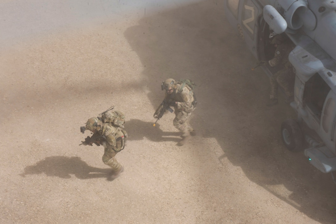 Airmen exit an aircraft with their weapons drawn.