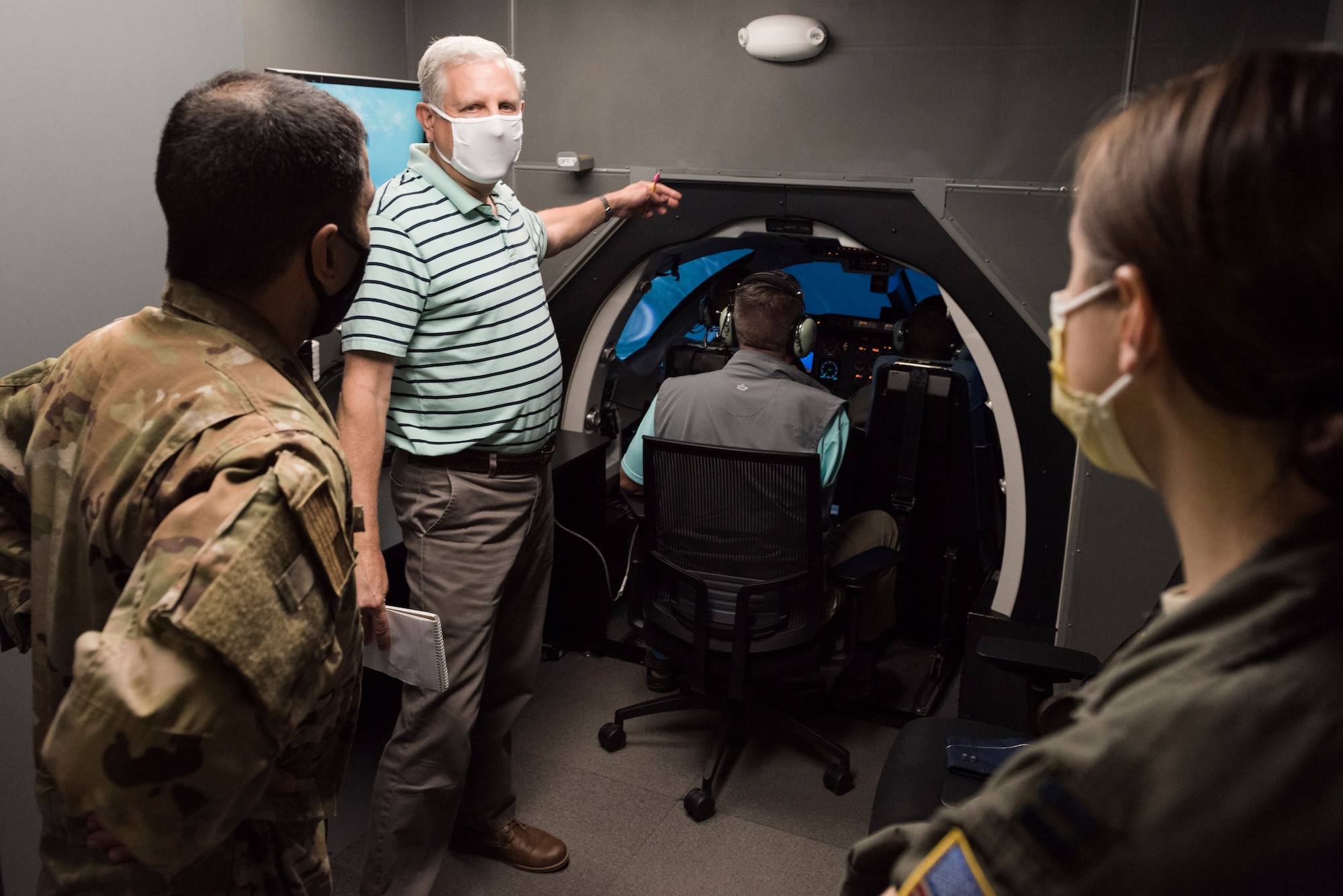 David Loftus, 47th Operations Group lead simulation instructor, demonstrates the tight quarters within the flight simulators to Lt. Col. Hafez Nasr, 47th Medical Group chief of aerospace medicine, and Capt. Susan Ching, 47th Flying Training Wing public health emergency officer,, Aug. 6, 2020 at Laughlin Air Force Base, Texas. The 47th Operations Group plans to purchase face shields for simulation instructors and provide them with latex gloves to prevent as much contact on the higher-contact surfaces. (U.S. Air Force photo by Senior Airman Anne McCready)