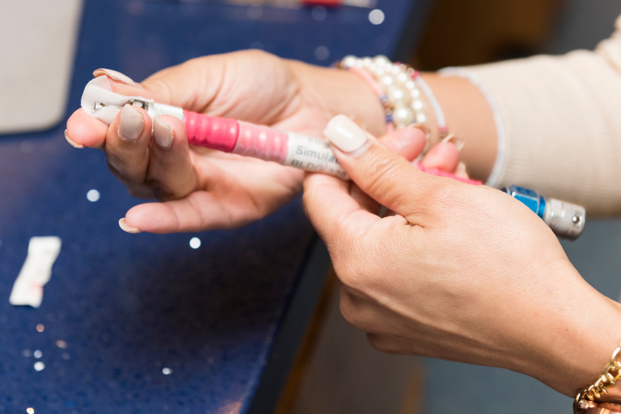 Kathy Santiago, 47th Operations Group dispatcher, sanitizes an emergency oxygen hose, an item each student uses during simulations, Aug. 6, 2020 at Laughlin Air Force Base, Texas. In addition, there are sanitizing stations available throughout the building for hands and other high-contact items such as pencils. (U.S. Air Force photo by Senior Airman Anne McCready)