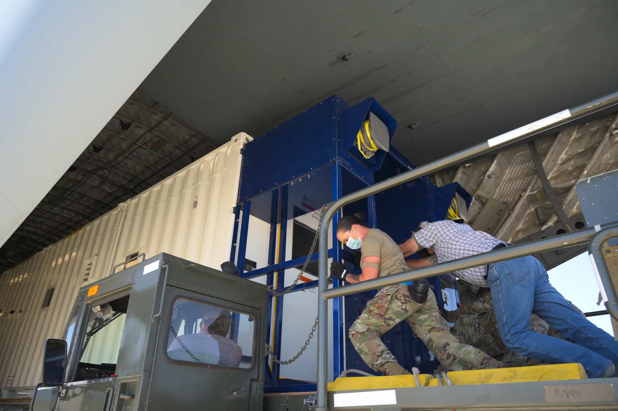 U.S. Air Force personnel push a Negatively Pressurized Conex into a C-17 Globemaster III from atop a Tunner 60k loader