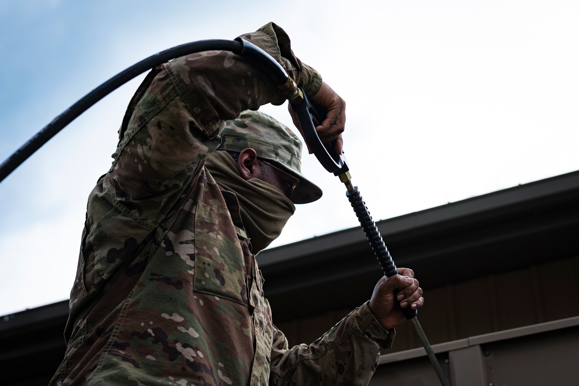 A photo of an Airman holding a pressure washer spray gun