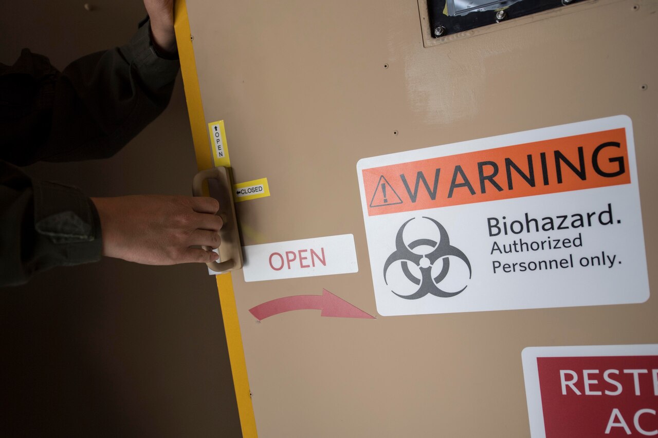 A medic opens the door to a negatively pressured conex.