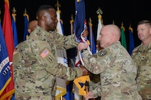 Maj. Gen Frank Muth, commanding general of U.S. Army Recruiting command, passes the Medical Recruiting Brigade colors to Col. Gary Cooper, the incoming commander, during a ceremony at Fort Knox’s Waybur Theater July 10, 2020. (Charles Leffler, Fort Knox Visual Information)