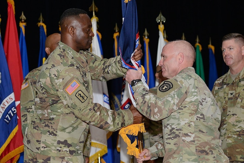 Maj. Gen Frank Muth, commanding general of U.S. Army Recruiting command, passes the Medical Recruiting Brigade colors to Col. Gary Cooper, the incoming commander, during a ceremony at Fort Knox’s Waybur Theater July 10, 2020. (Charles Leffler, Fort Knox Visual Information)