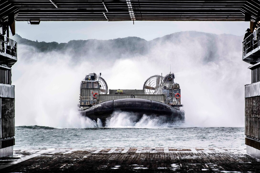 An air-cushioned landing craft approaches the well deck of a ship.
