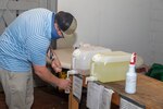Carrier Assistant Project Superintendent (APS) Tim Riley fills up a hand sanitizer bottle at the refillable station in Bldg. 298.