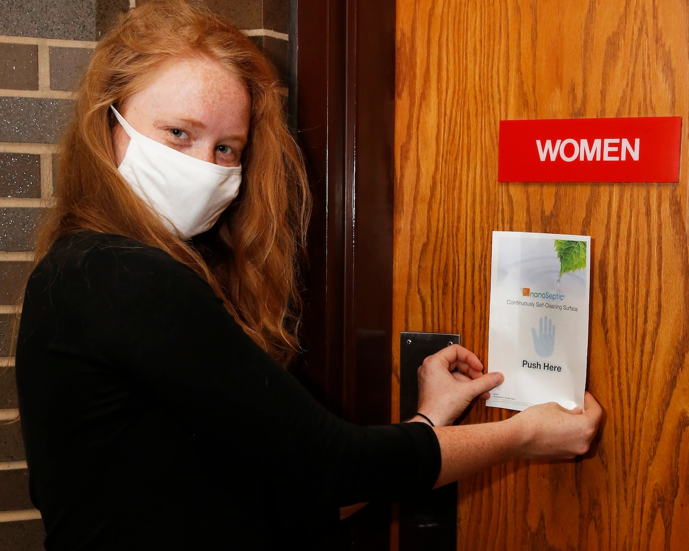 Nuclear Engineer (Code 2310.4) Cynthia Raines applies a NanoSeptic Protective Sheet to the high-touch area of a women’s bathroom door in Bldg. 1500 at Norfolk Naval Shipyard.