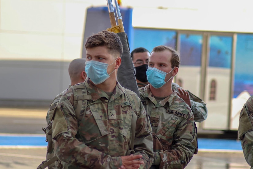 Soldiers wearing face masks arrive at their deployment location.