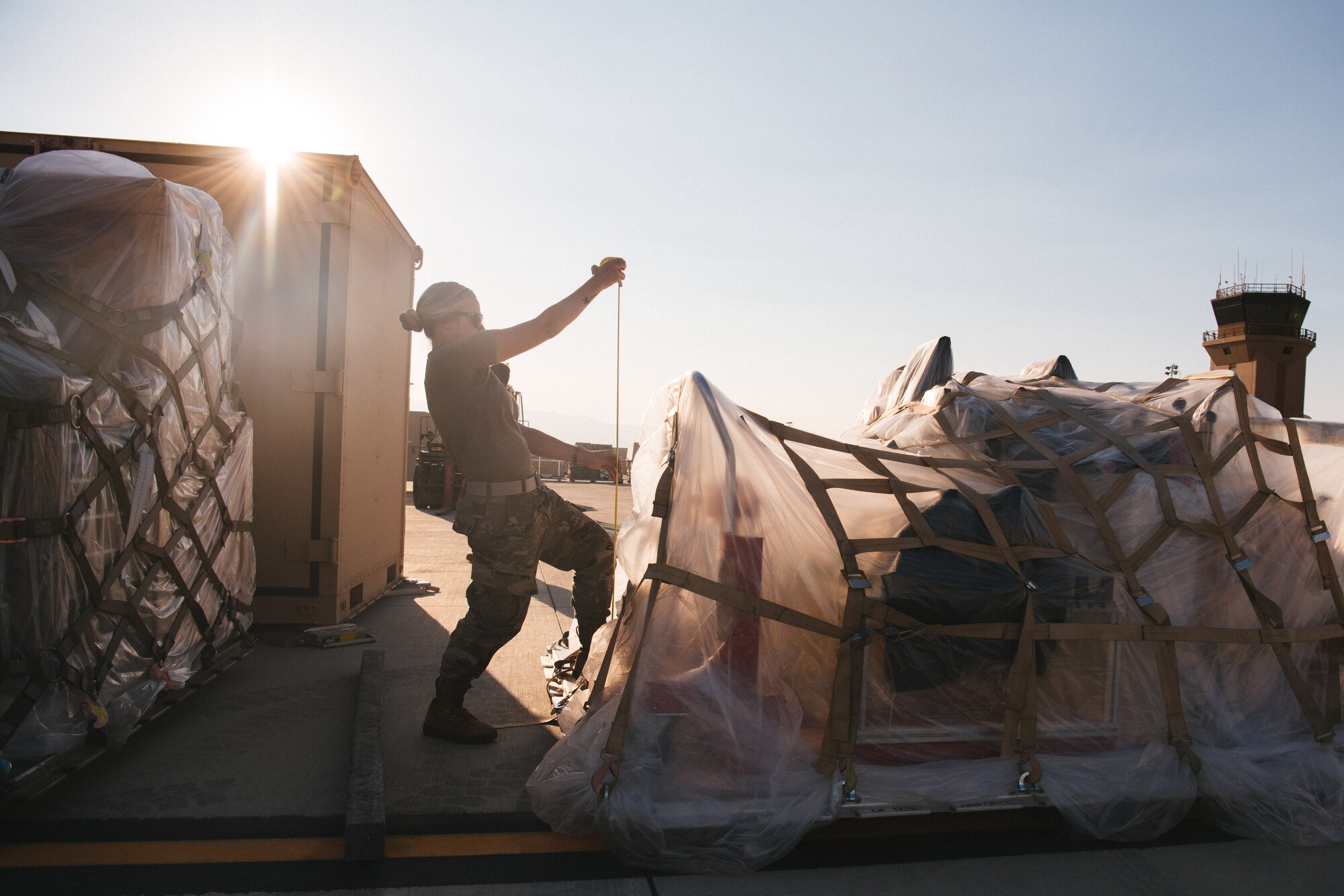 Tech. Sgt. Hayley, 432nd Support Squadron air terminal section chief, holds a measuring tape while being backlit by the sun.