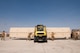 A forklift holds an MQ-9 connex as Airmen move to lay weights underneath it.