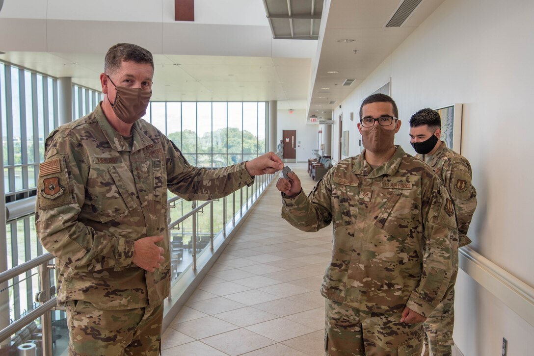 Two Airmen holding AFSC Commander's coin