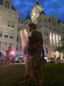 A Utah Air National Guard Airman stands with a riot shield to protect a building in downtown Salt Lake City, Utah