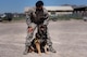 Jojo shows his fangs midbark as his trainer holds his leash.