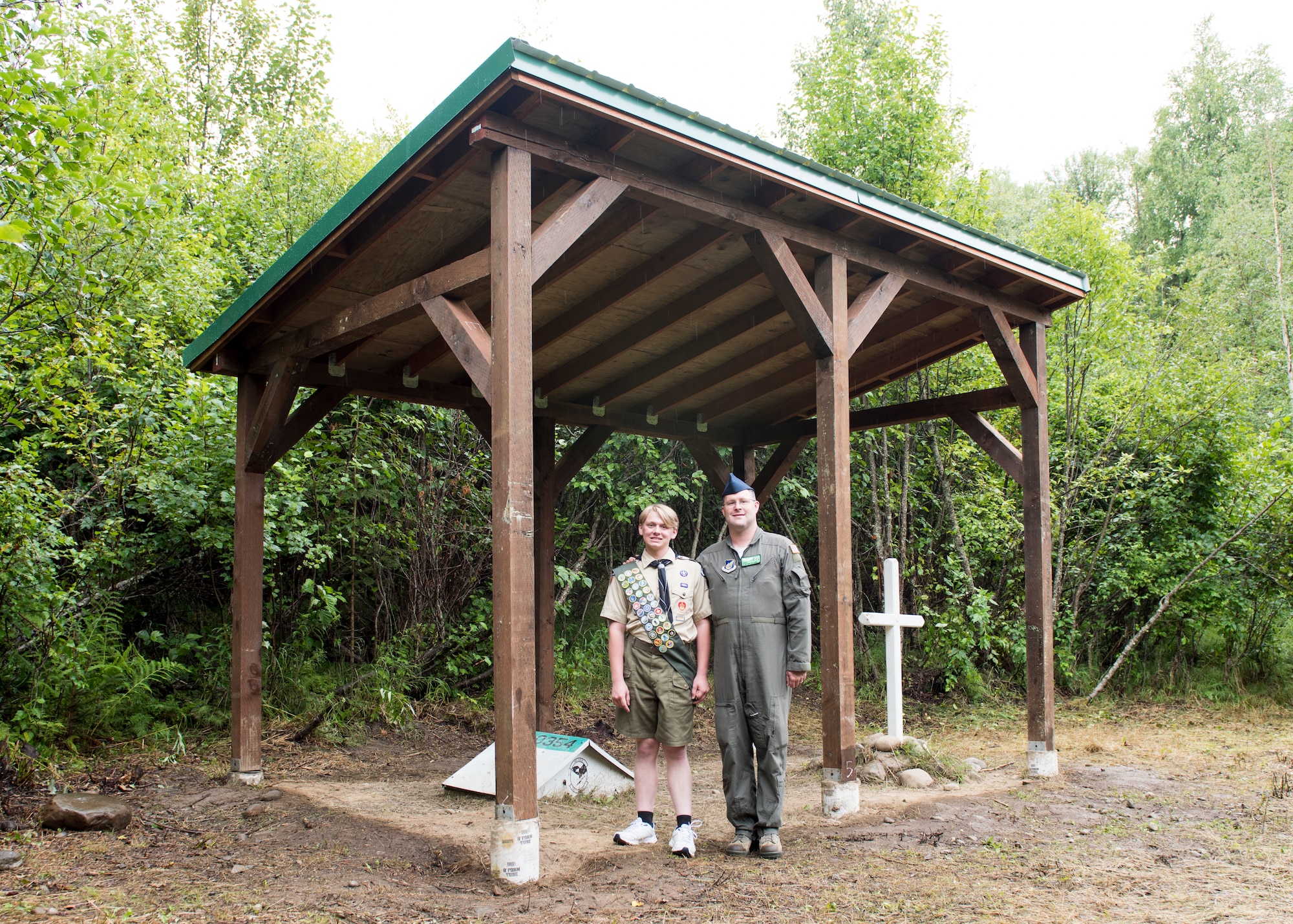 Daryn Moore, a member of Scouts BSA Troop 54, and his father, U.S. Air Force Tech. Sgt. Clayton Moore, 962nd Airborne Air Control Squadron communications systems operator and Troop 54 assistant scoutmaster, pose for a photo at Joint Base Elmendorf-Richardson, Alaska, Aug. 11, 2020. Daryn built a pavilion with help from Clayton, other Scouts and members of the 962nd Airborne Air Control Squadron to protect the memory box and cross at the Yukla 27 crash site from rain and snow. The pavilion is Daryn’s Eagle Scout Service Project, a project that benefits the community as a requirement to gain the rank of Eagle Scout, the highest rank in Scouting.