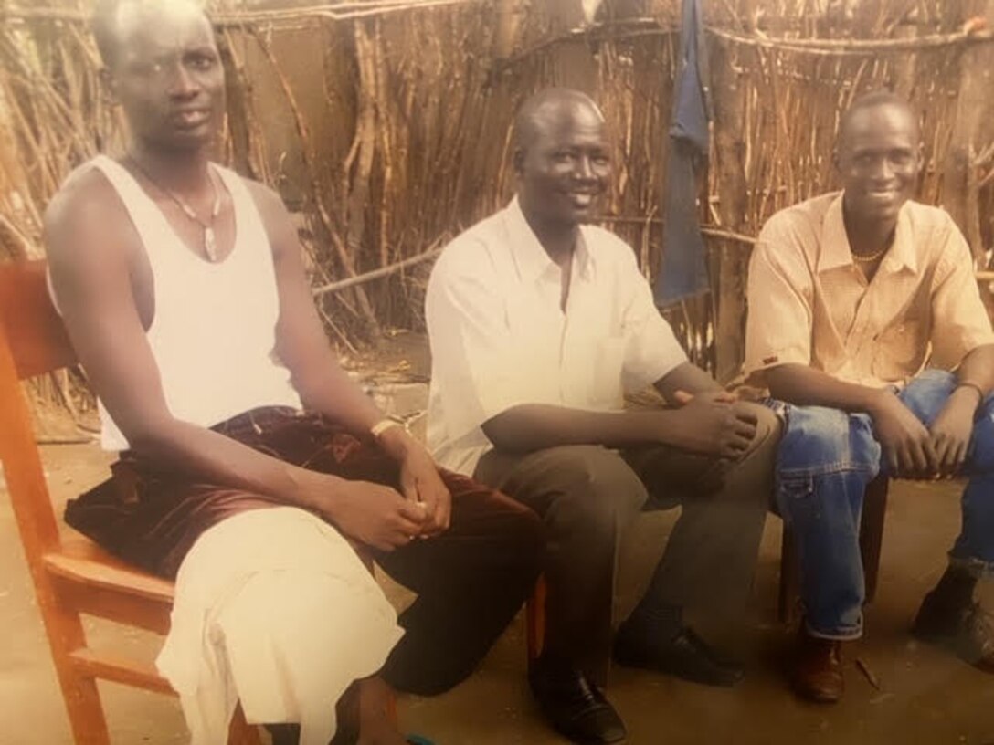 Gatluak Chuol Juach, the father of Airman 1st Class Nyarauch Chuol, passenger operations representative with the 32nd Aerial Port Squadron, and his brothers sit outside of the family hut in Gambela, Ethiopia in 2011.