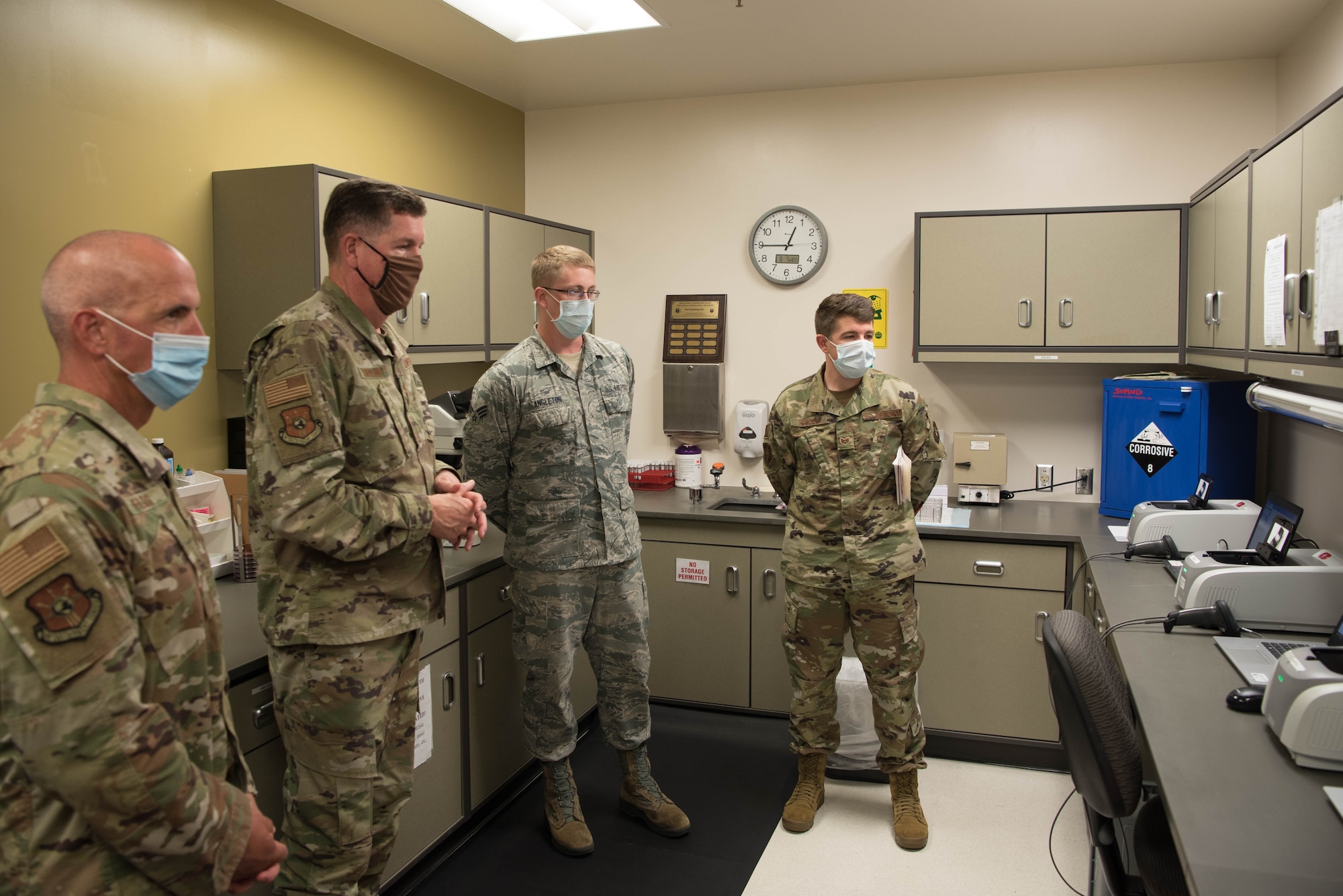 Four Airmen looking at medical testing equipment in laboratory