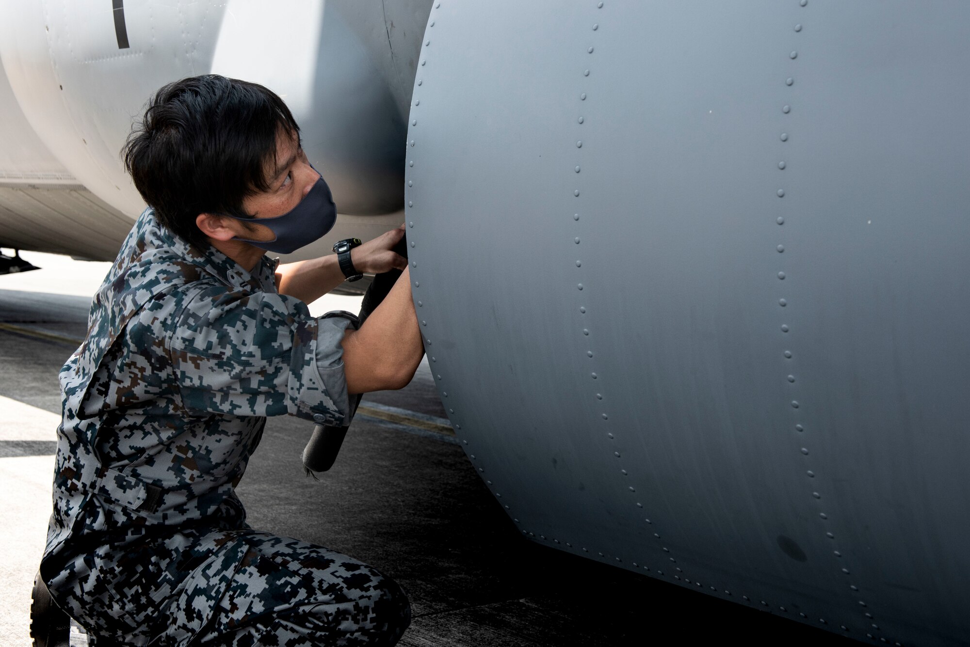 A Koku-Jieitai (Japan Air Self-Defense Force) member scans a C-130J super Hercules for potential threats during a training scenario as a portion of the bilateral aircraft security training at Yokota Air Base, Japan, August 7, 2020.