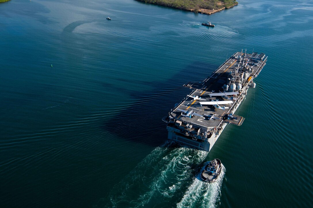 A military ship carries vintage military aircraft into a harbor.