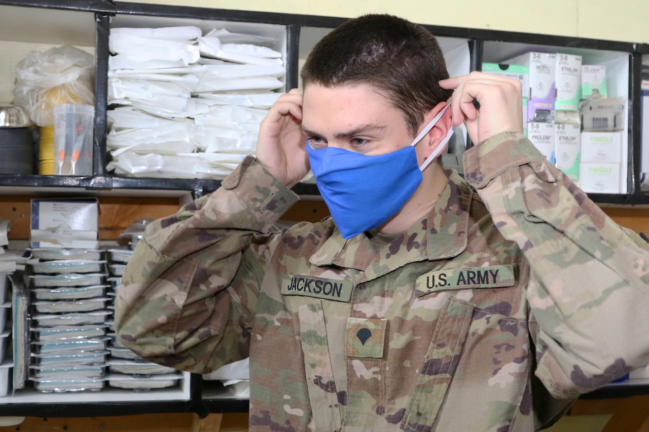 A soldier puts on a blue face mask.