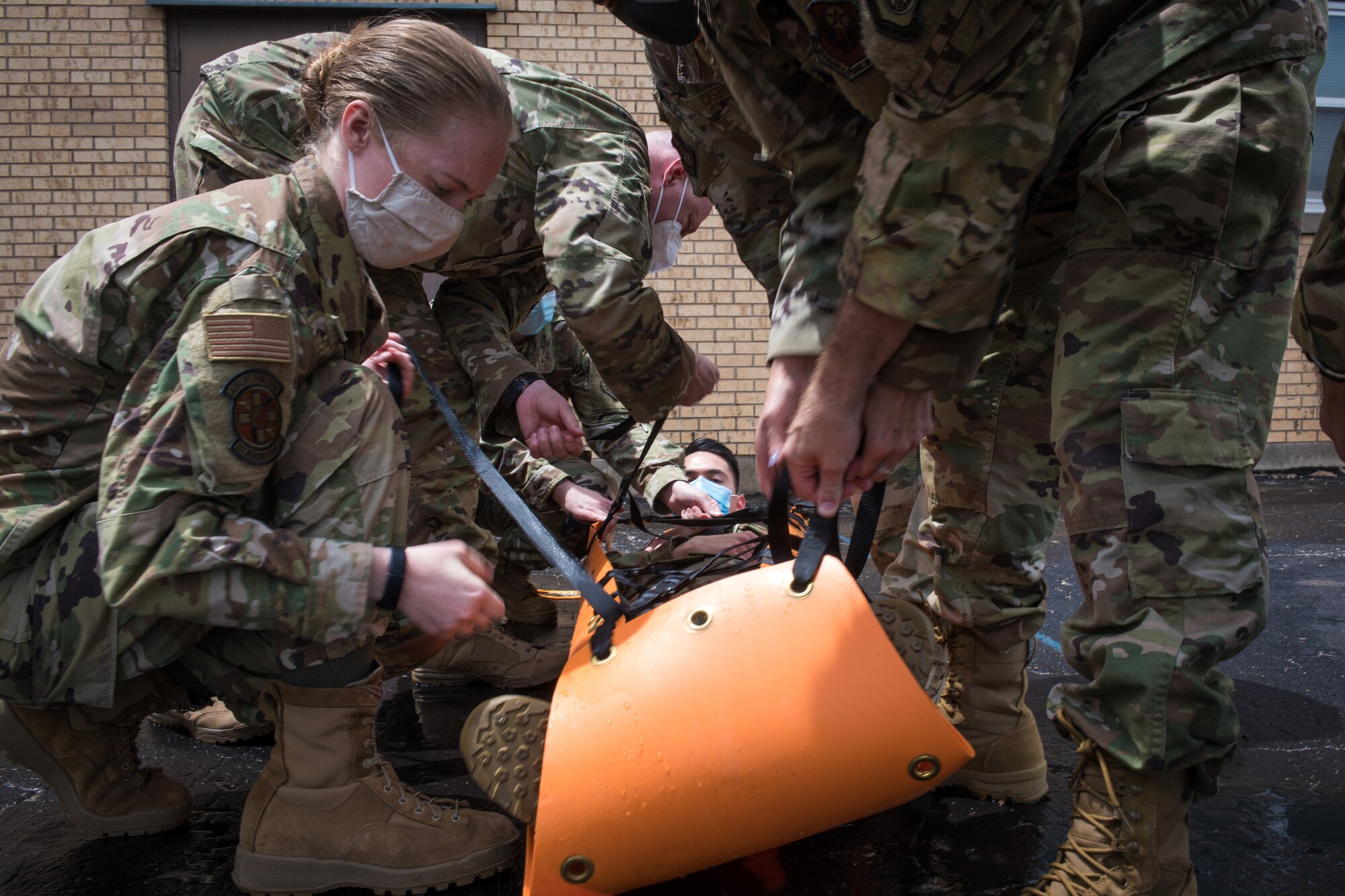 Airmen strap a simulated patient into a stretcher