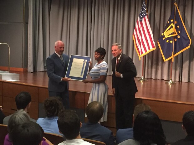 Brian Davis, left, director, Defense Personnel and Family Support Center, and Gregory J. Slavonic, right, assistant secretary of Navy Manpower and Reserve Affairs, present the 2019 Judith C. Gilliom Award for Outstanding Workforce Recruitment to Timberlain Woodruff, Navy Warfare Development Command (NWDC) management analyst on July 18. NWDC develops and integrates innovative solutions to complex naval warfare challenges to enhance current and future warfighting capabilities. (U.S. Navy photo courtesy of Norman R. Wood, Jr., NWDC)