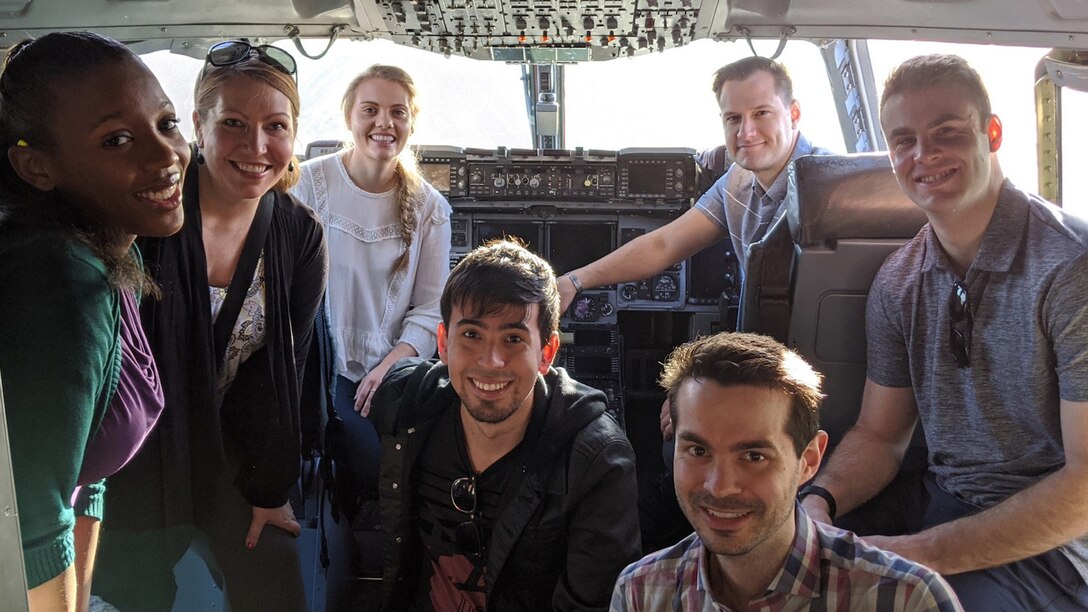 A photo of the U.S. Massachusetts Institute of Technology (MIT) Artificial Intelligence Accelerator team smiling at the camera in the cockpit after a tour on the C-17 Globemaster III.