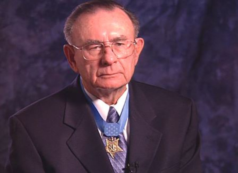 An older man in a suit wears a Medal of Honor.