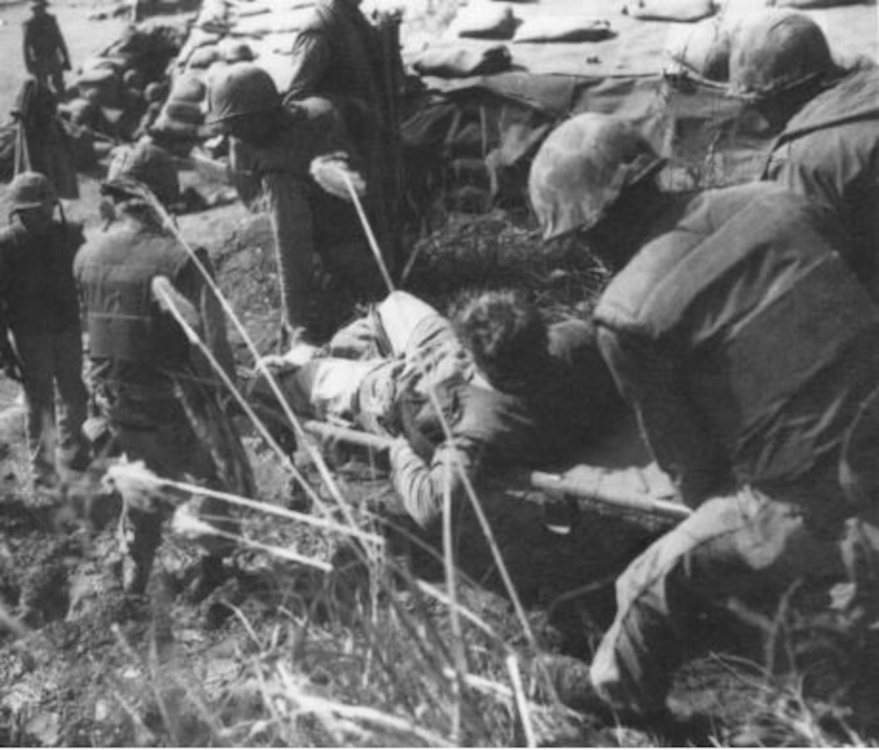 A man on a stretcher is carried by four other men.