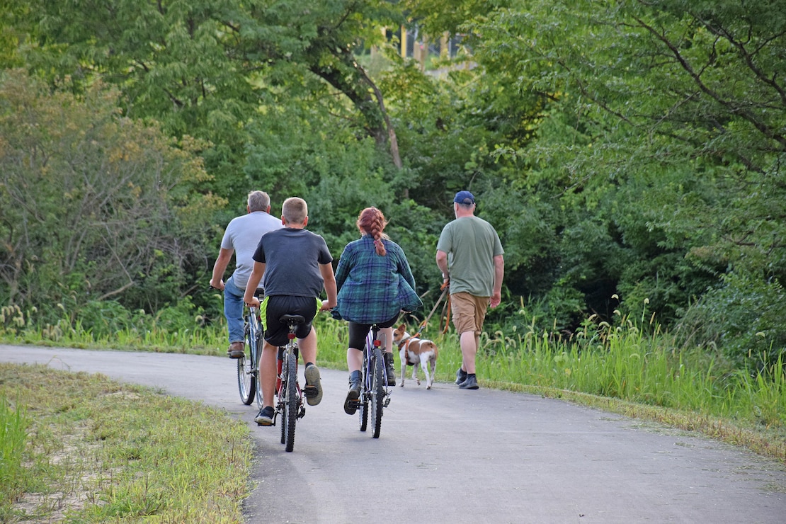 A group of bicyclists pass a man walking his dog on the Volksweg Trail near Lake Red Rock.