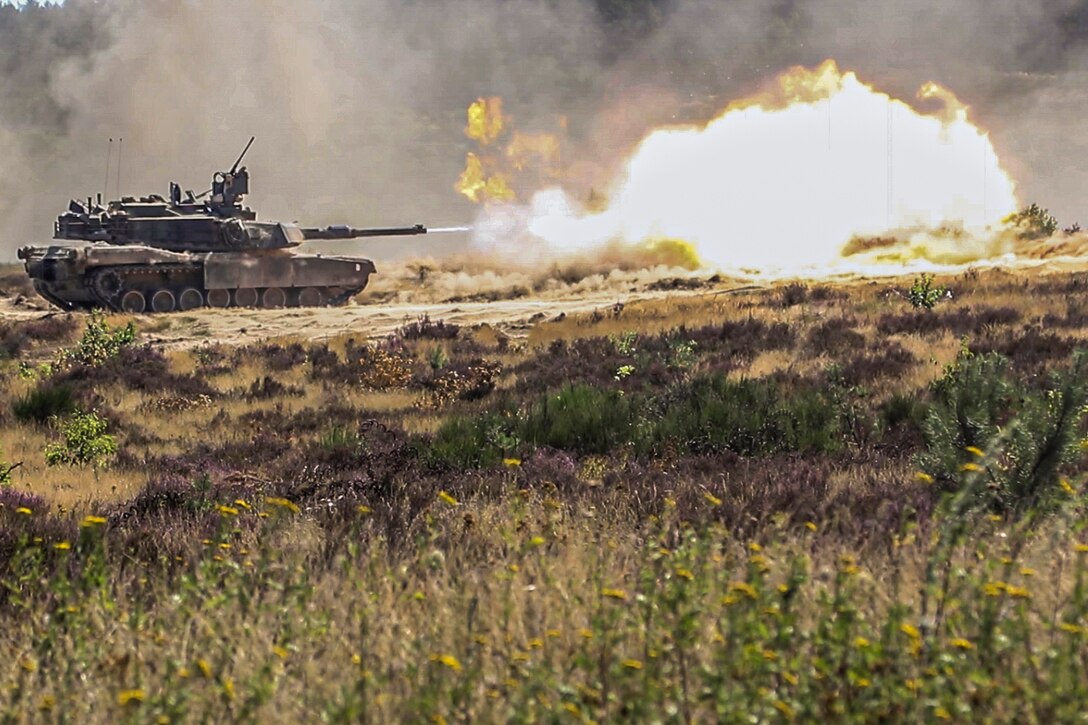 A tank fires at a target in a desert-like area.