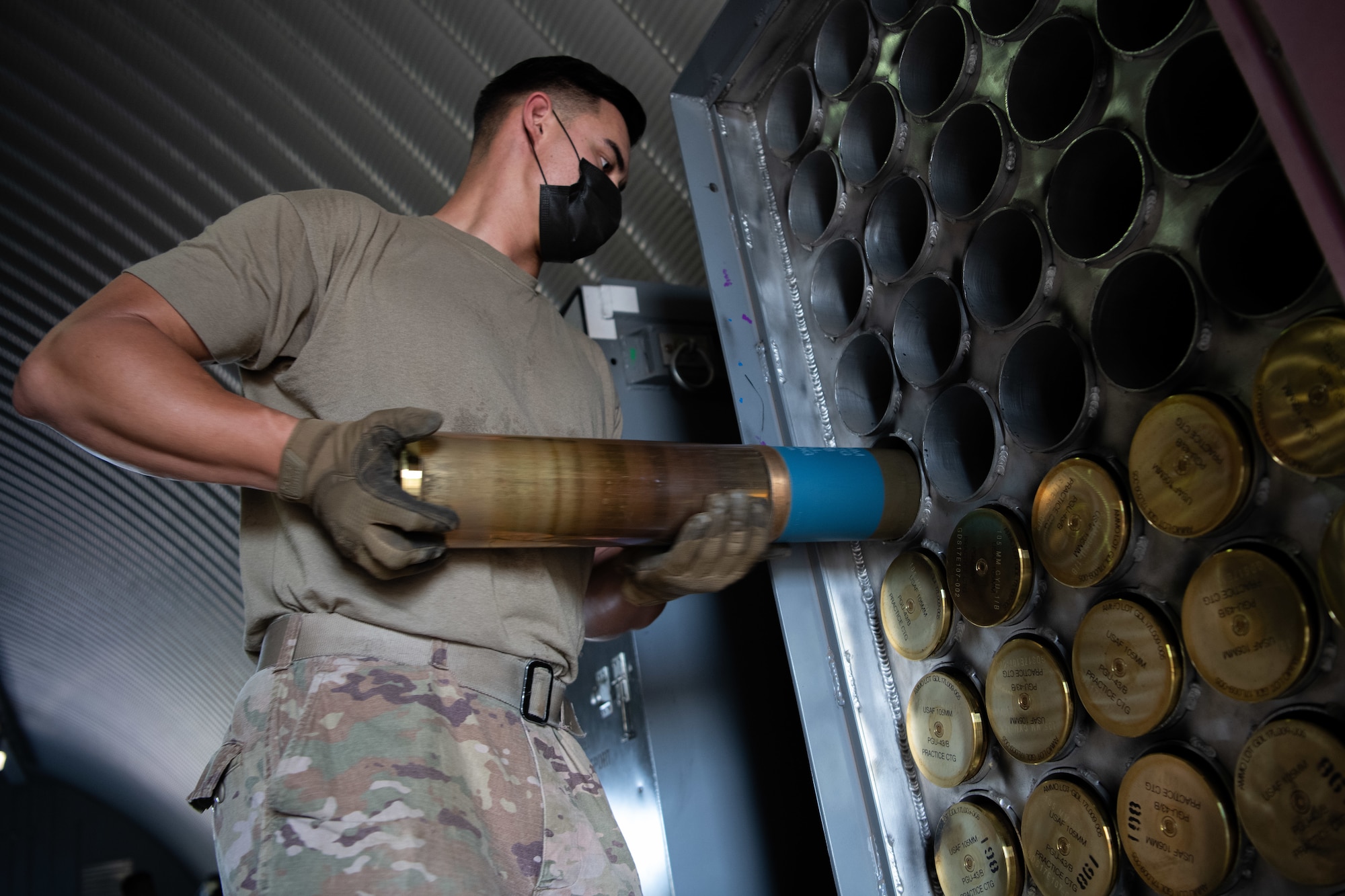 Senior Airman Cody Heathcock, a conventional maintenance specialist assigned to the 27th Special Operations Maintenance Squadron munitions flight, loads a 105 MM round into a temporary storage container at Cannon Air Force Base, N.M., July 22, 2020. 105 MM rounds are loaded into these containers until they are prepared for movement on trailers and stored until needed.  (U.S. Air Force photo by Senior Airman Maxwell Daigle)