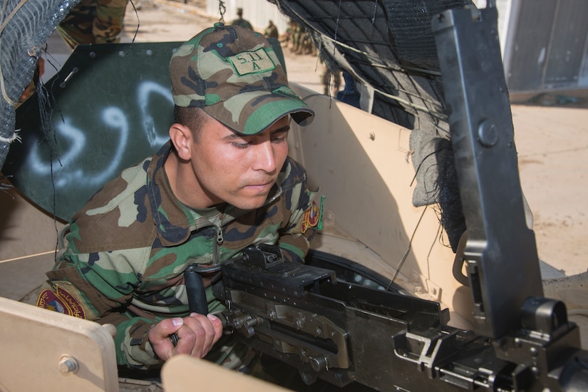 A man in a military uniform performs operations on a large gun.