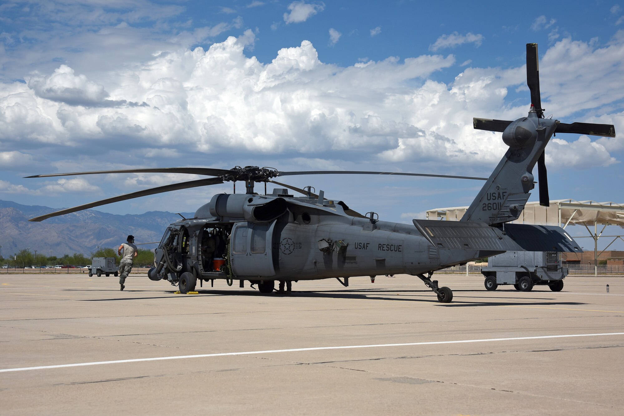 Photo of an Air Force Airman running around an HH-60G Pavehawk on a military flightline