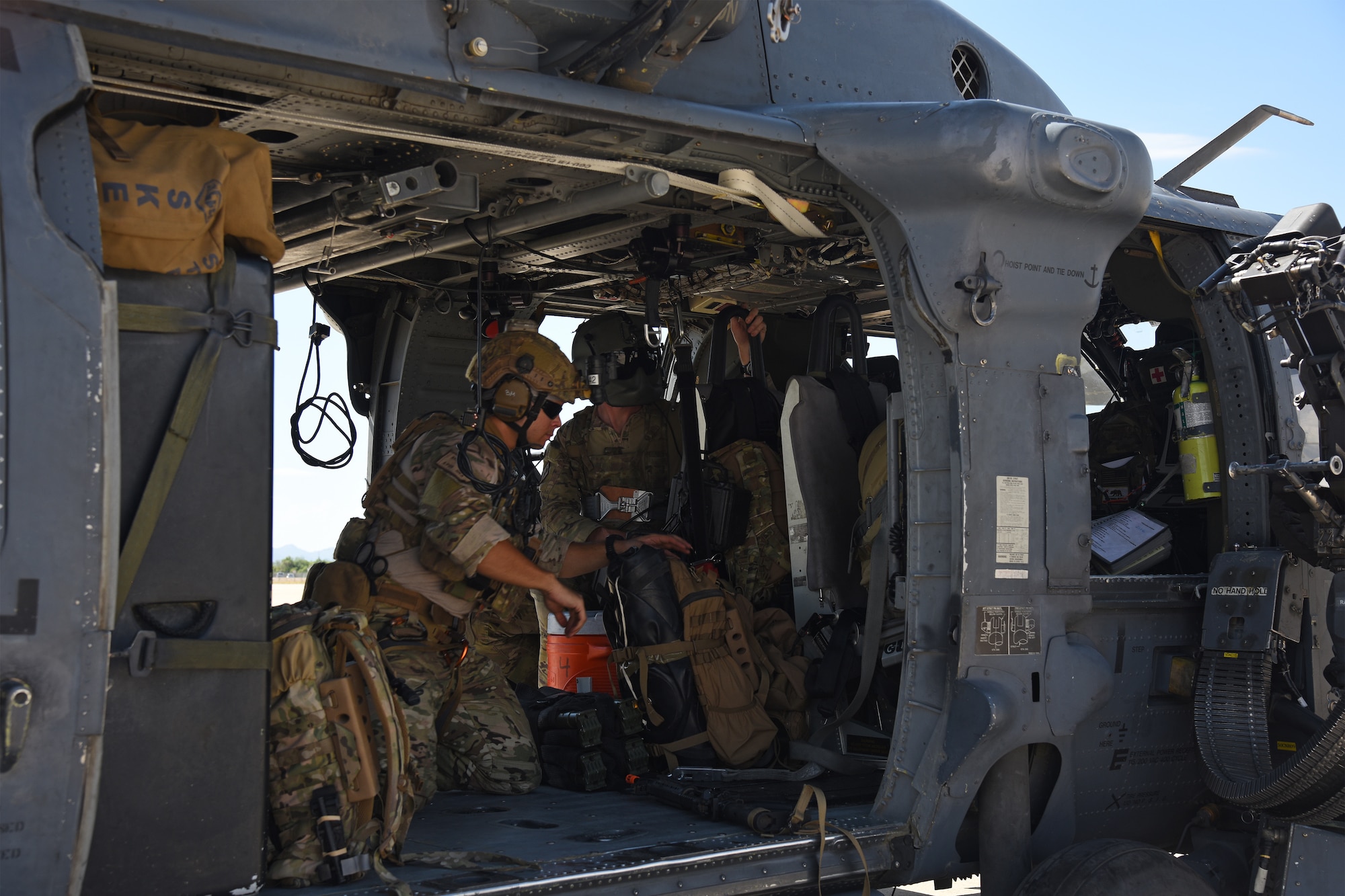 Photo of Air Force Airman inside an HH-60G Pavehawk on a military flightline