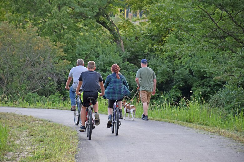 A group of bicyclists pass a man walking his dog on the Volksweg Trail near Lake Red Rock.