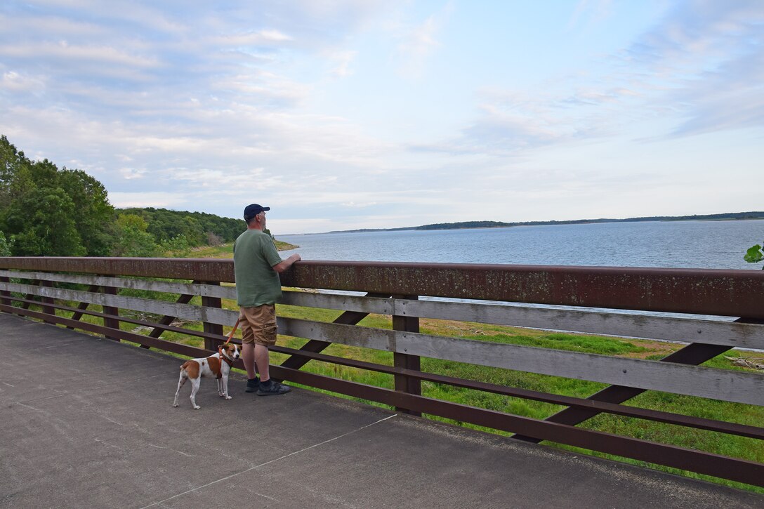 A man walking his dog on the Volksweg Trail stops to look out at Lake Red Rock near Pella, Iowa.